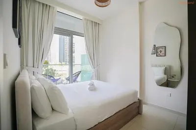 a bedroom with a white bed with a large window at Bnbeyond's Serene Poolside Bliss in Dubai