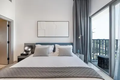 a white bedroom with a large bed and a balcony at ALiving Modern & Chic 1BR I MAG960 in Dubai