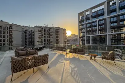 a rooftop patio with chairs and tables on a building at Chic Retreat 1Bedroom with Pool view in Dubai