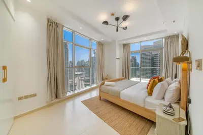 a bedroom with a large bed and large windows at Cityscape & Coastal Charm Elegant 2BR Seaside in Dubai Marina