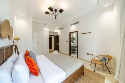 a bedroom with a large bed and a chair at Cityscape & Coastal Charm Elegant 2BR Seaside in Dubai Marina