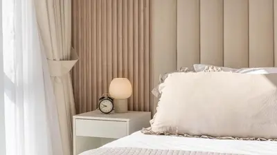 a bed with a white pillow and a clock on a night stand at High-Floor 1BR New Design Steps to JBR Beach in Dubai