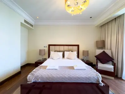 a bedroom with a large bed and a chandelier at Luxury 2BR plus Maidrm at Grandeur Res Palm Jumeir in Dubai