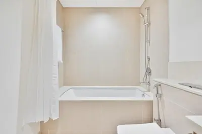 a white bathroom with a tub and a toilet at Venetian - Wake up to Burj Khalifa views in Downtown Dubai in Dubai