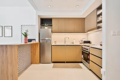 a kitchen with a stainless steel refrigerator and wooden cabinets at Venetian - Wake up to Burj Khalifa views in Downtown Dubai in Dubai