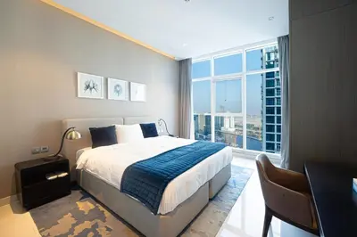 a bedroom with a bed and a desk and a large window at Venetian - Luxe Living 1 BR with Stunning Sky Line Views in Dubai