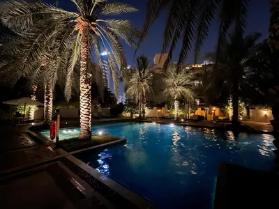 a large swimming pool with palm trees at night at Front Burj Khalifa 2BR in Old town community in Dubai