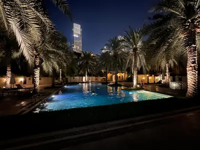 a swimming pool with palm trees at night at Front Burj Khalifa 2BR in Old town community in Dubai