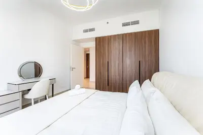 a bedroom with a white bed and a wooden door at HAVN - 1 Bedroom in Madinat Jumeirah Living in Dubai