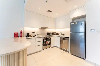 a kitchen with white cabinets and a stainless steel refrigerator at HAVN - 1 Bedroom in Madinat Jumeirah Living in Dubai