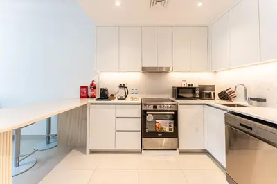 a kitchen with white cabinets and a stainless steel oven at HAVN - 1 Bedroom in Madinat Jumeirah Living in Dubai