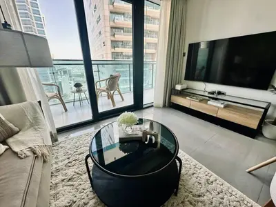 a living room with a glass table and a television at Stylish 1br Merano Tower Pool Parking in Dubai