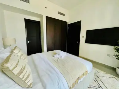 a bedroom with a white bed and a flat screen tv at Stylish 1br Merano Tower Pool Parking in Dubai