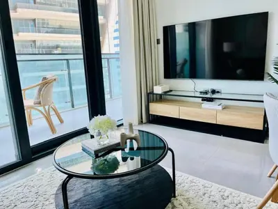 a living room with a large tv and a glass table at Stylish 1br Merano Tower Pool Parking in Dubai