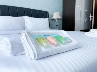 three towels are stacked on a white bed at Stylish 1-Bedroom-Sleeps 4- Apartment -Bayz by Danube, Business Bay-29 in Dubai