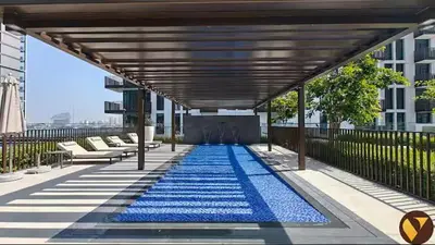 a large blue swimming pool under a wooden canopy at Vogue Creek Harbour Creek Crescent Waterfront Living Close to Downtown, Burj Khalifa and Dubai Mall, One Bedroom Apartment with Balcony and City View, Access to all Amenities in Dubai