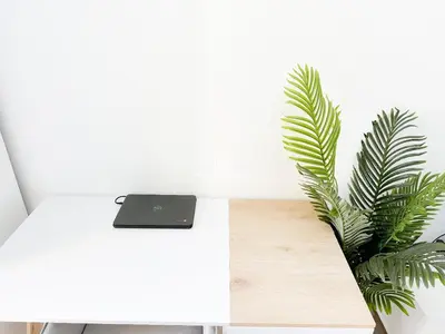 a laptop on a white desk next to a plant at Fully Furnished Studio at Spring Oasis in Dubai Silicon Oasis in Dubai