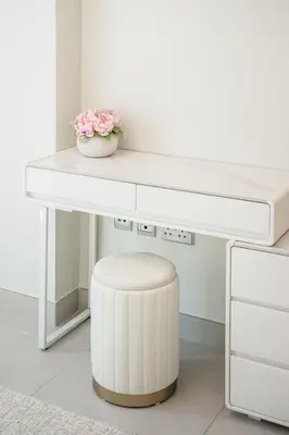 a white desk with a vase of flowers and a stool at Luxury unit in the Heart of Dubai Hills in Dubai