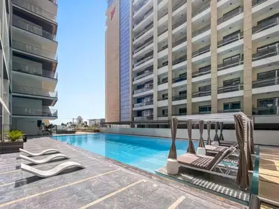 a swimming pool with lounge chairs next to a building at Vogue Al Jadaf Binghatti Creek near Festival Mall, Three Bedroom Apartment with Balcony and City View, Access to all Amenities in Dubai