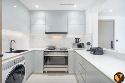 a white kitchen with a stove and a dishwasher at Vogue Al Jadaf Binghatti Creek near Festival Mall, Three Bedroom Apartment with Balcony and City View, Access to all Amenities in Dubai
