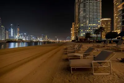 a row of lounge chairs on a beach at night at Romantic basic apertmen in Dubai