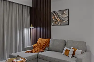 a living room with a gray couch with an orange blanket at Dreamy Apartment,Pool with Burj khalifa View ,5Min Walk to Dubai Mall in Dubai