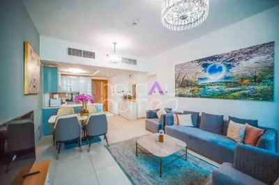 a living room with a blue couch and a table at Stylish 2BR in Continental Tower Dubai Marina in Dubai