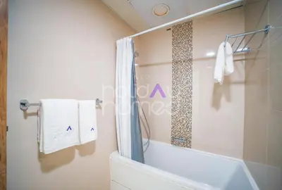 a bathroom with a tub and a shower with towels at Stylish 2BR in Continental Tower Dubai Marina in Dubai