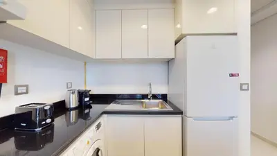 a small kitchen with white cabinets and a sink at Vacationer I JVC Gem 1 Bedroom I Free Pool, Gym, Parking & Wi-Fi in Dubai