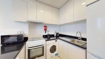 a kitchen with a washing machine and a microwave at Vacationer I JVC Gem 1 Bedroom I Free Pool, Gym, Parking & Wi-Fi in Dubai