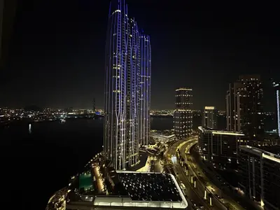 a tall building with blue lights on it at night at SUNRISE HOMES - Stylish 1-BR with Incredible Views - Creekside in Dubai