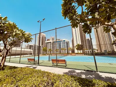 a tennis court with two benches next to a fence at SUNRISE HOMES - Stylish 1-BR with Incredible Views - Creekside in Dubai