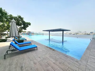 two blue lounge chairs and an umbrella on a swimming pool at SUNRISE HOMES - Stylish 1-BR with Incredible Views - Creekside in Dubai