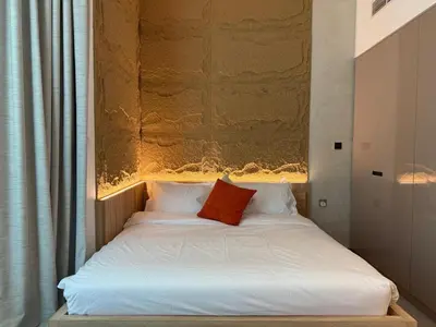 a white bed with a red pillow on it at Cozy Studio with Balcony Pool View - Business Bay in Dubai