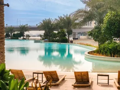 a swimming pool with chairs and a building at 1BD Apartment at Creek Beach with Lagoon Access in Dubai