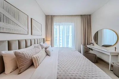 a white bedroom with a large bed and a mirror at 1BD Apartment at Creek Beach with Lagoon Access in Dubai