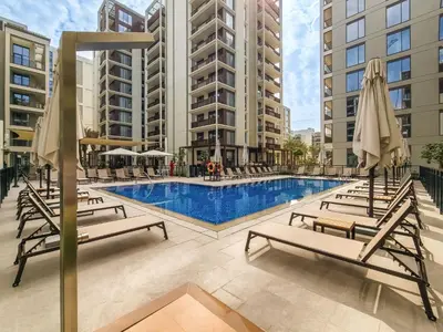 a pool with chairs and umbrellas next to buildings at 1BD Apartment at Creek Beach with Lagoon Access in Dubai