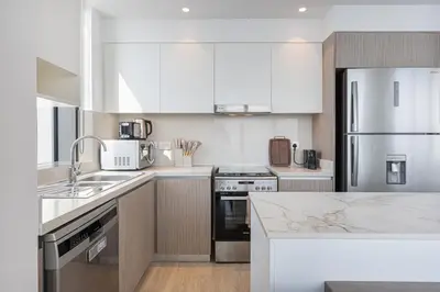 a kitchen with white cabinets and stainless steel appliances at Stunning Home with Creek and Downtown Views in Dubai