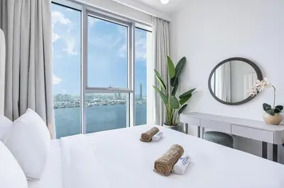 a white bedroom with a large window and a desk at Stunning Home with Creek and Downtown Views in Dubai
