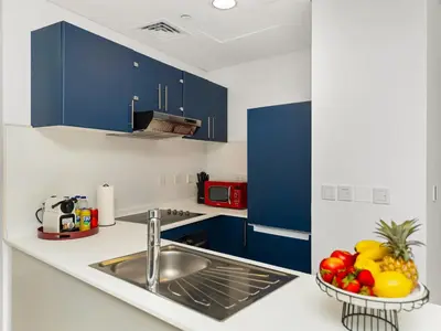 a kitchen with blue cabinets and a sink and fruit at Amazing Design Colorfull Flat Palm Jumeirah View in Heart of Marina in Dubai