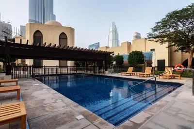 a large swimming pool with chairs and a building at Cozy 2BDR Residence in Dubai's Souk Al Bahar in Dubai