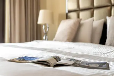 an open book on a white bed with a lamp at Cozy 2BDR Residence in Dubai's Souk Al Bahar in Dubai
