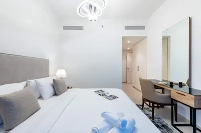 a bedroom with a white bed with a desk and a mirror at Ultimate Luxury 3BDR With Burj Khalifa view in Dubai