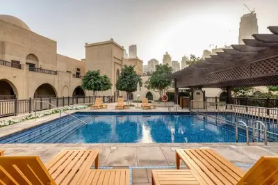 a large swimming pool in a building with chairs at Gorgeous 1BDR with Burj Khalifa & Fountain Views in Dubai