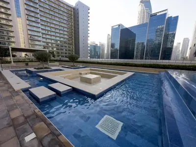a pool with blue water in a city with buildings at Brand new 1BDR in Vera- Business Bay in Dubai