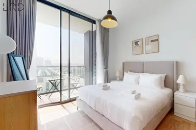 a bedroom with a large white bed and a balcony at Brand New and Modern 1BR in Dubai