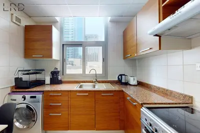 a kitchen with wooden cabinets and a sink and a window at Cozy Studio in Dubai Marina in Dubai