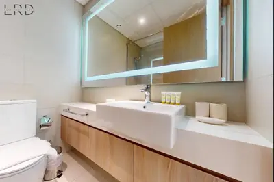 a bathroom with a sink and a mirror and a toilet at Cozy 1BR with Canal View in Dubai