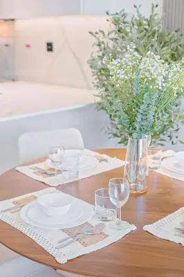 a table with plates and glasses and a vase of flowers at PVH - Vibrant 1BR - Binghatti Corner in Dubai
