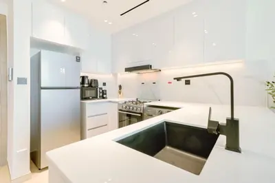 a white kitchen with a sink and a refrigerator at PVH - Vibrant 1BR - Binghatti Corner in Dubai